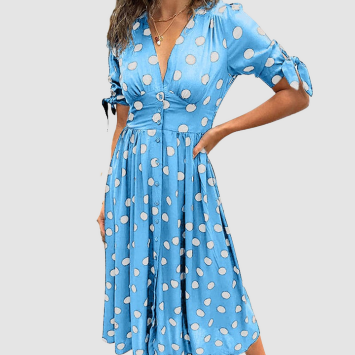 Light blue dress with white polka dots, V-neck, tied sleeves, knee-length, studio setting.