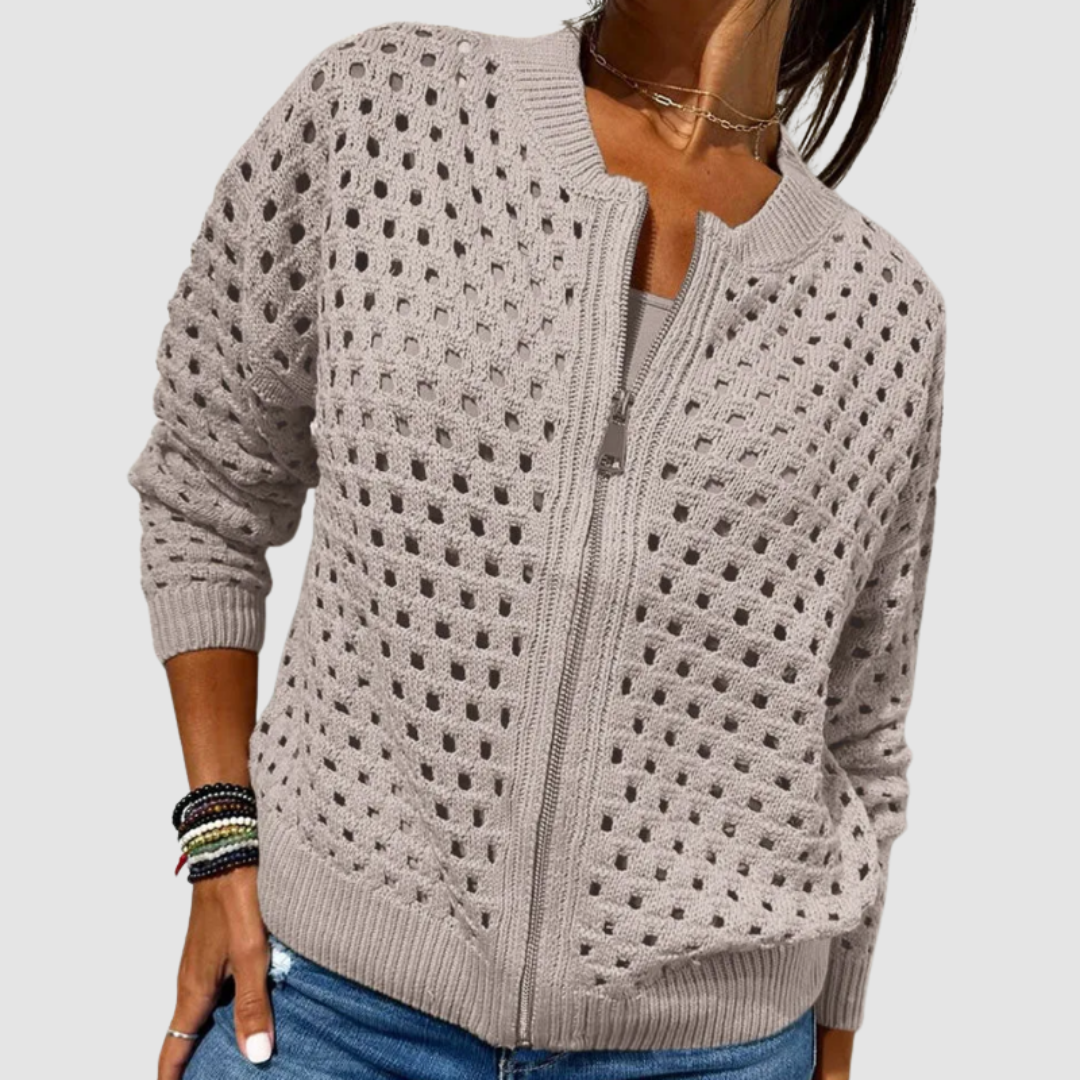 Soft gray knitted cardigan with a perforated design and front zipper, paired with casual jeans in a studio setting.