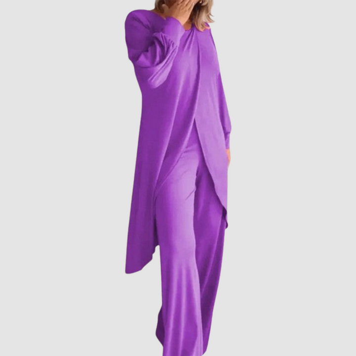 Model wearing a purple long-sleeve 2-piece set in a studio, hand covering face, white background.
