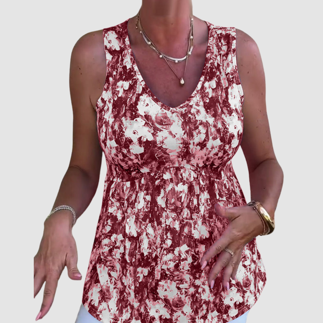 Woman gesturing while wearing a red and white sleeveless abstract pattern top in a studio setting.