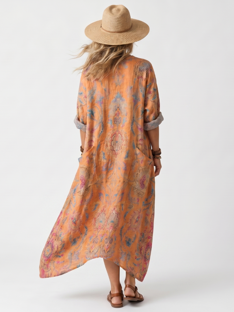 Back view of orange printed oversized pocket midi dress, styled with a hat and sandals in a studio setting.