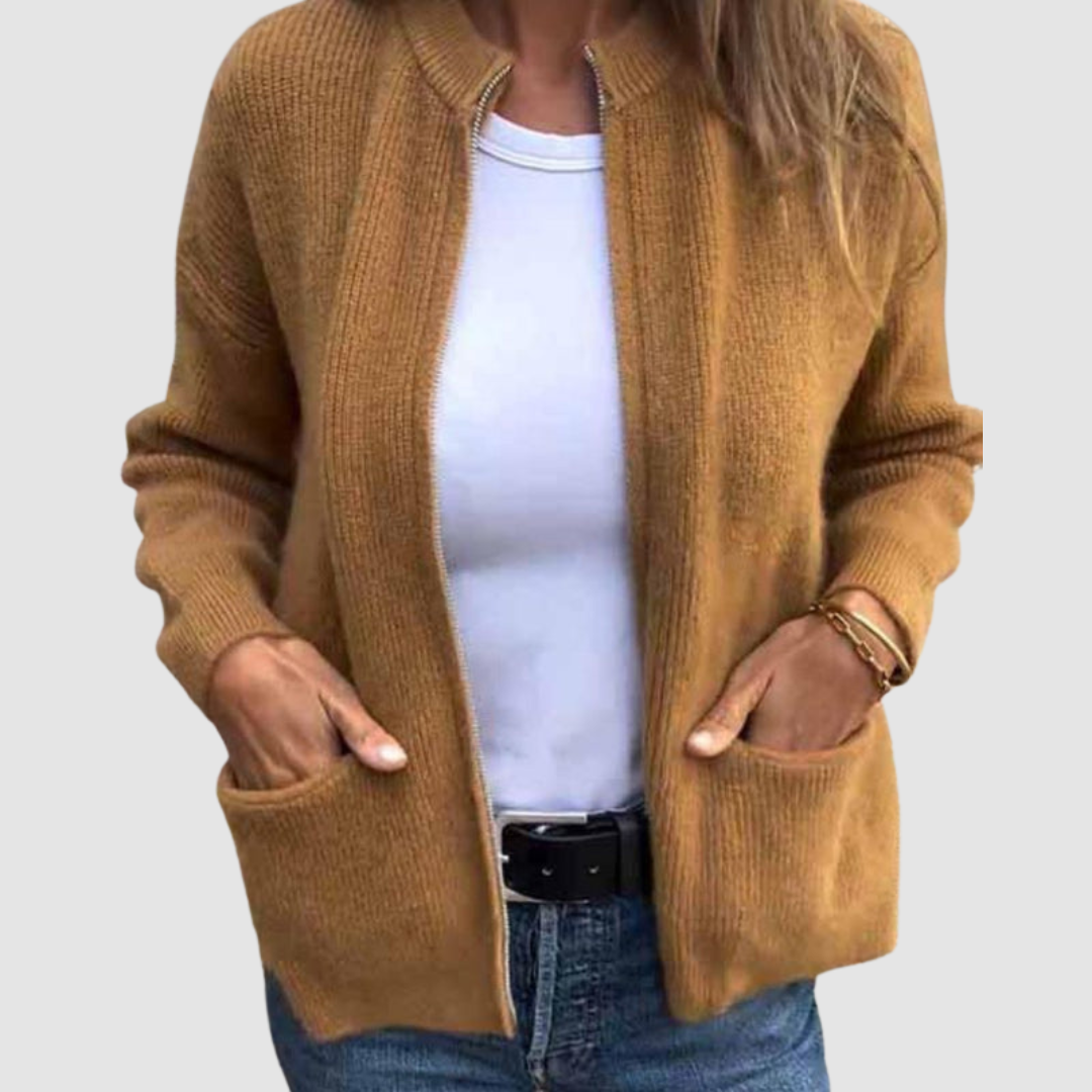 Brown cozy cardigan worn over a white t-shirt with hands in pockets. Neutral background.