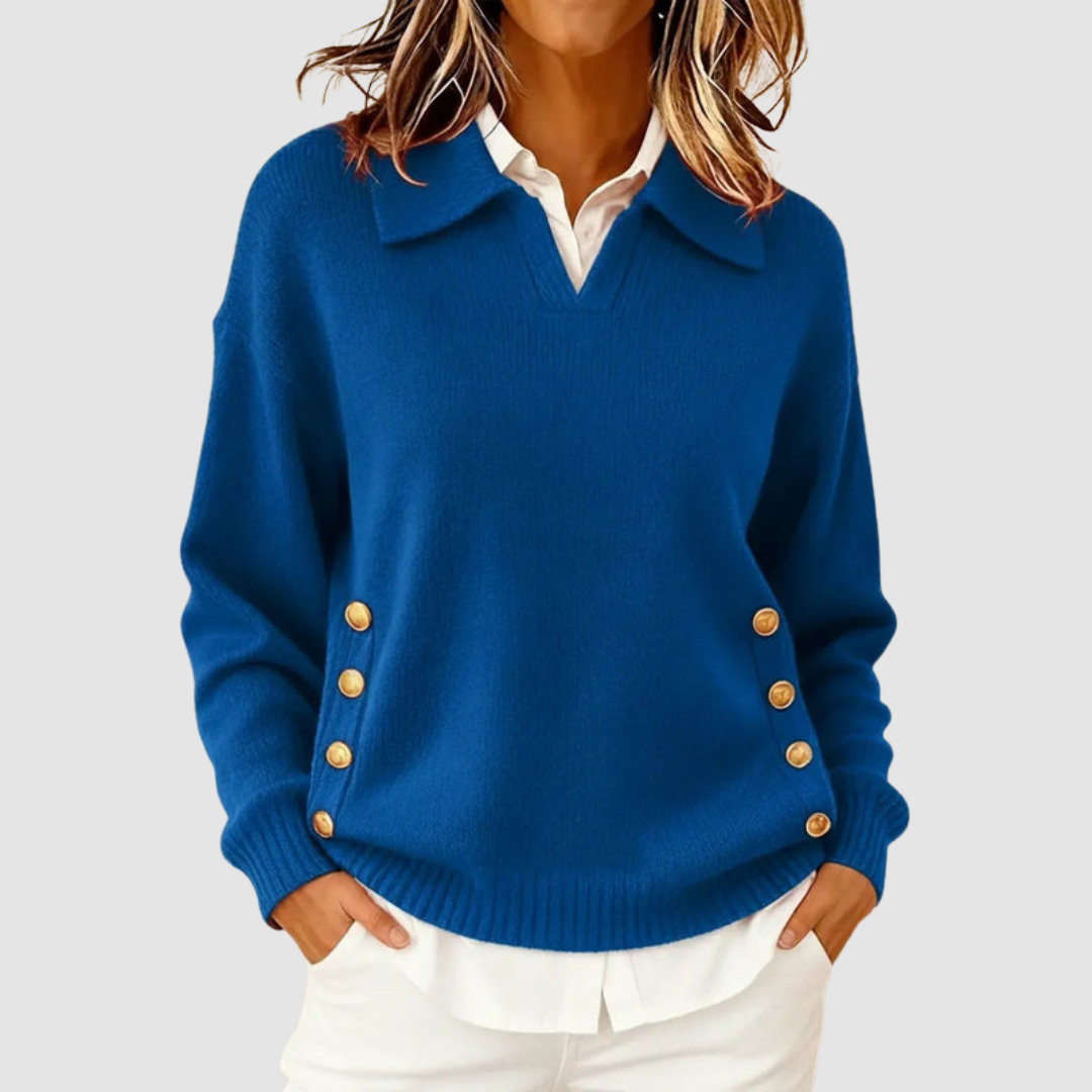Elegant blue knitted sweater with gold buttons on sides, worn over a white shirt against a light grey background.