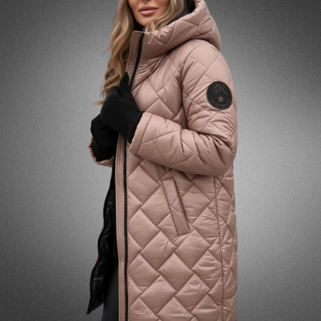 Woman in beige quilted jacket with hood in studio, wearing black gloves on a gradient background.