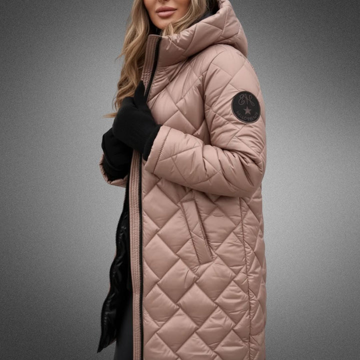 Woman in beige quilted jacket with hood in studio, wearing black gloves on a gradient background.