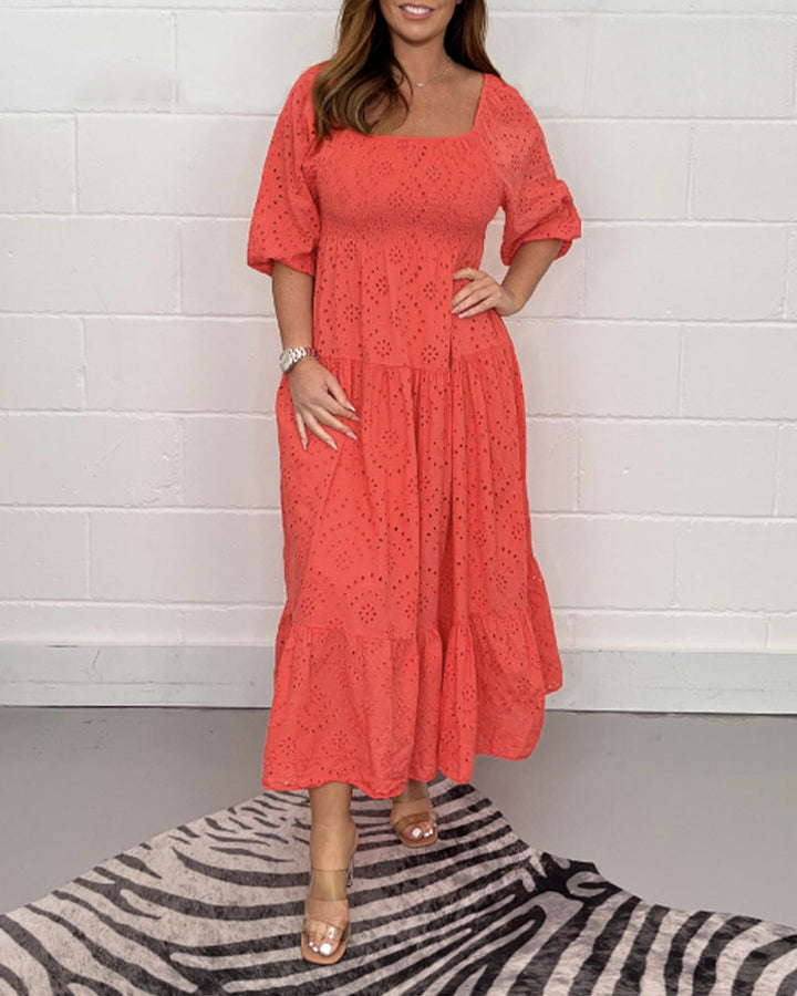 Red elegant dress with eyelet detailing, modeled against a white wall with zebra-patterned rug.