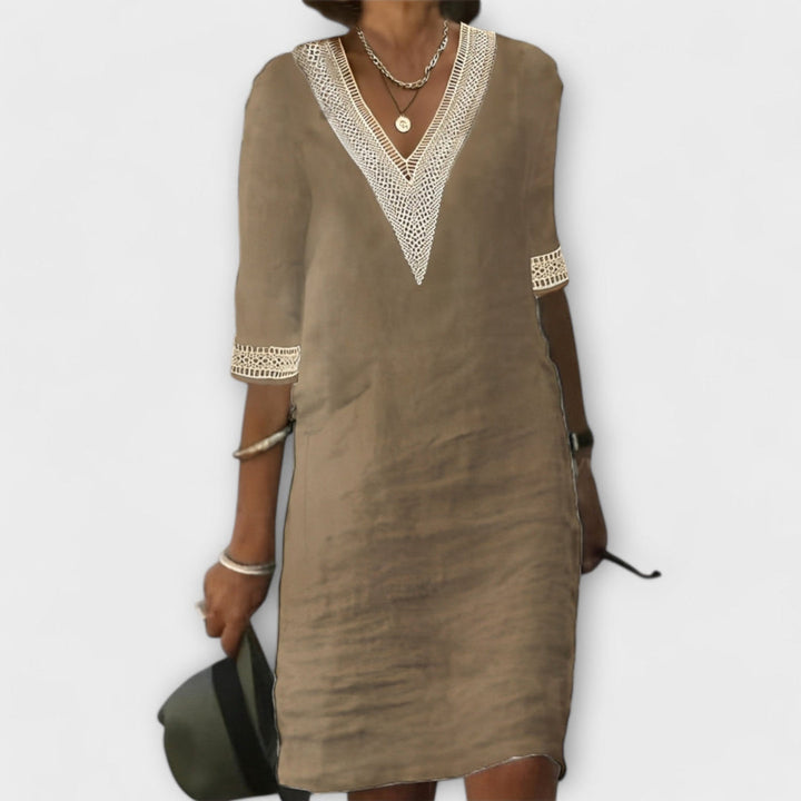 Beige elegant dress showcasing V-neck and lace trim, styled with silver accessories on a plain background.