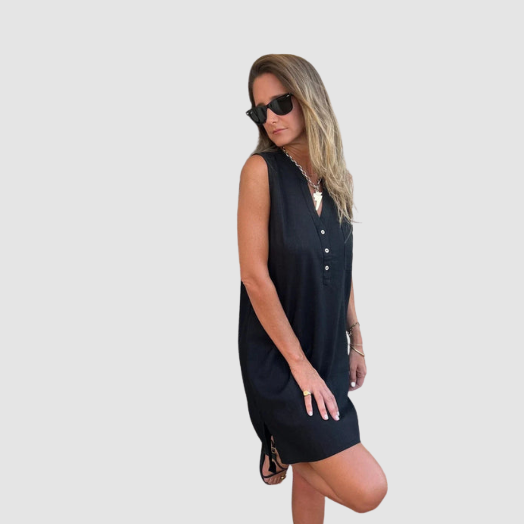 Woman wearing sunglasses, in a black sleeveless dress, posing sideways. Plain background.