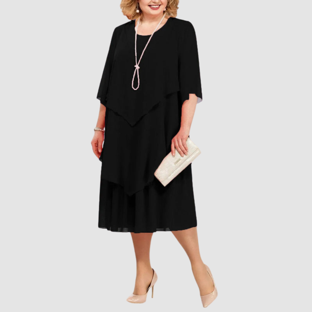 Black chiffon midi dress with layered design, worn with pearl necklace and beige clutch on white background.