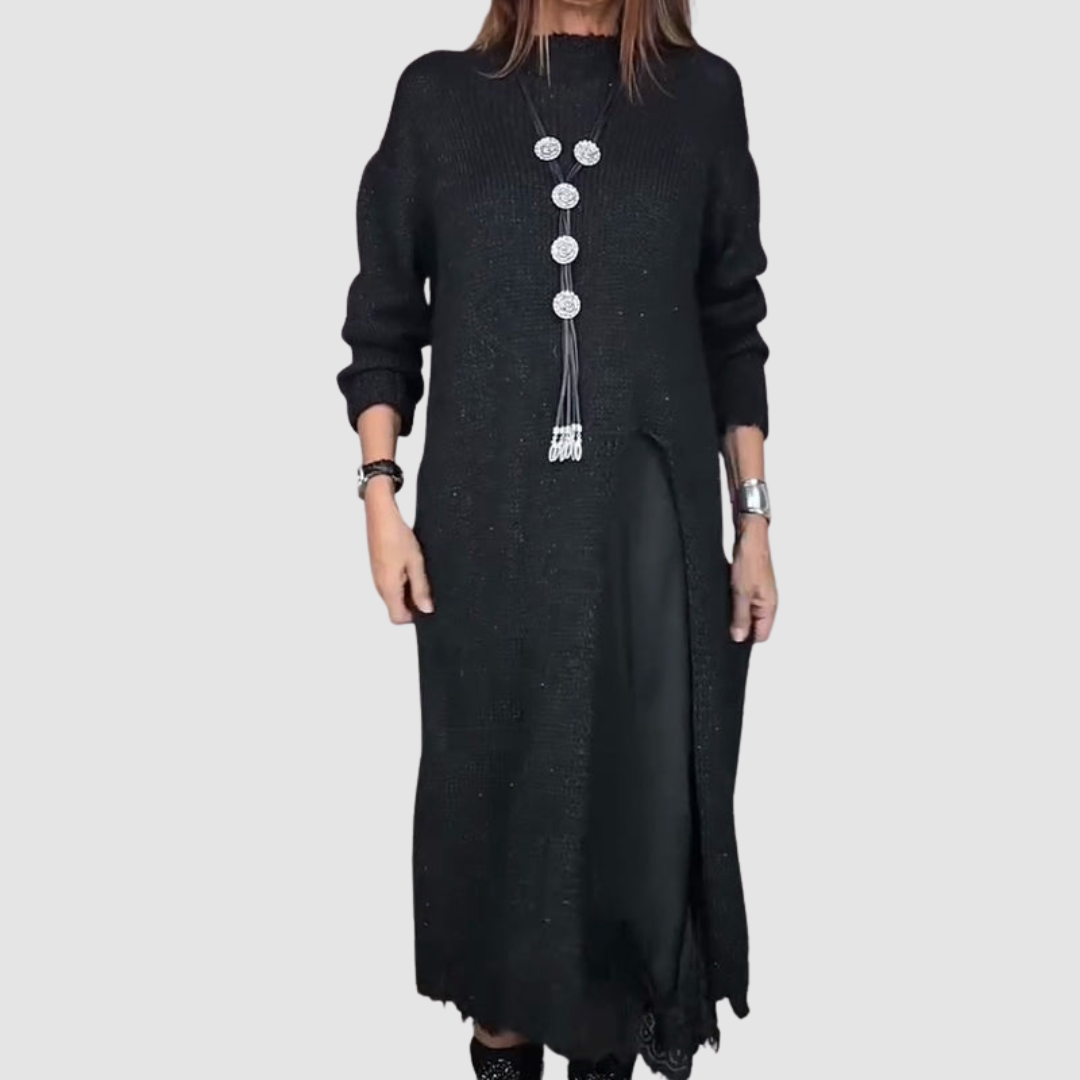 Black dress with layered skirt detail and statement necklace, woman posing in a studio setting.