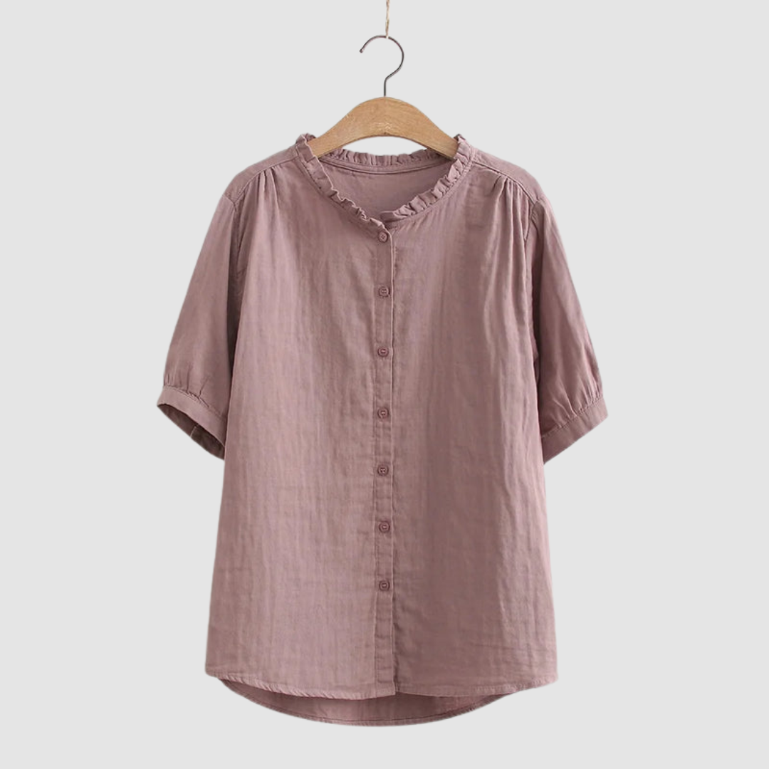 Dusty rose button-up shirt with ruffled collar on wooden hanger, studio background.