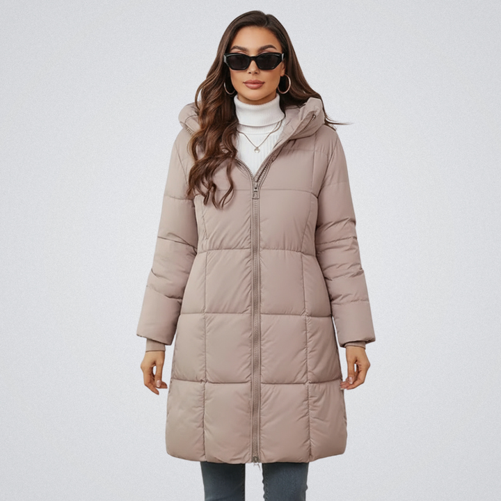 Woman in a light beige puffer coat with hood, wearing sunglasses and a white turtleneck, in a studio setting.