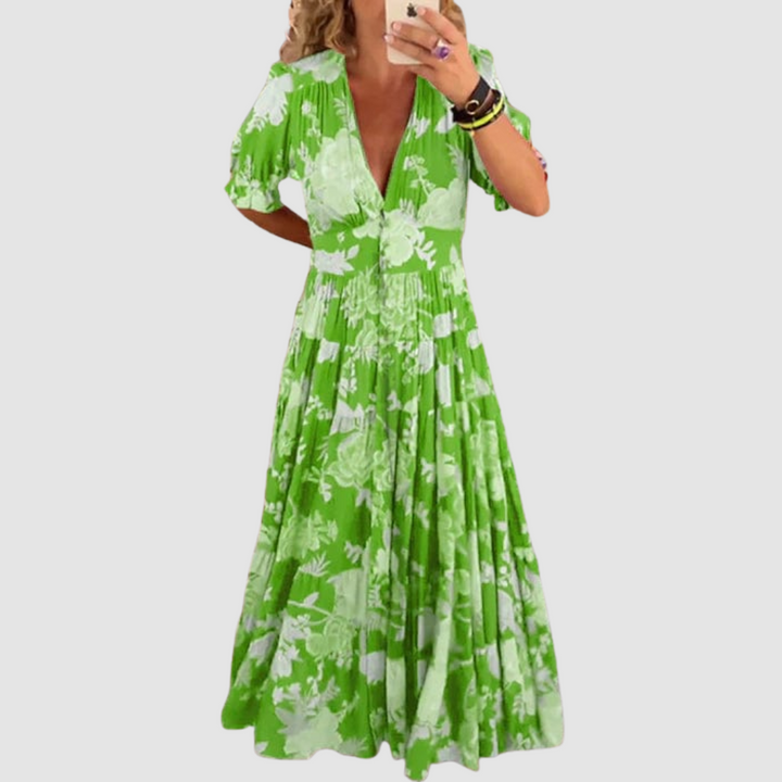 Green floral long dress with short sleeves, styled with a flowing skirt, set in front of a neutral backdrop.