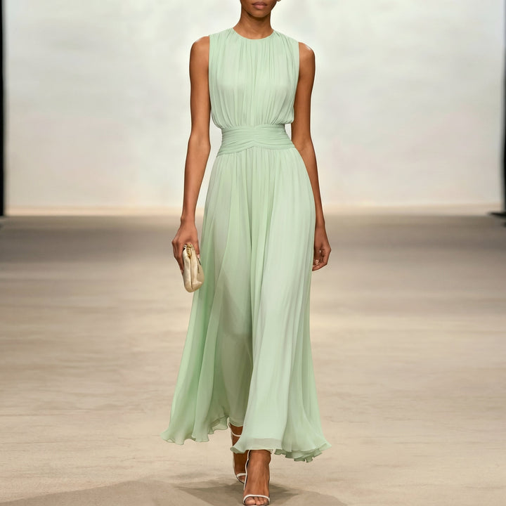Soft green elegant dress, flowing style, model holding clutch in indoor setting.