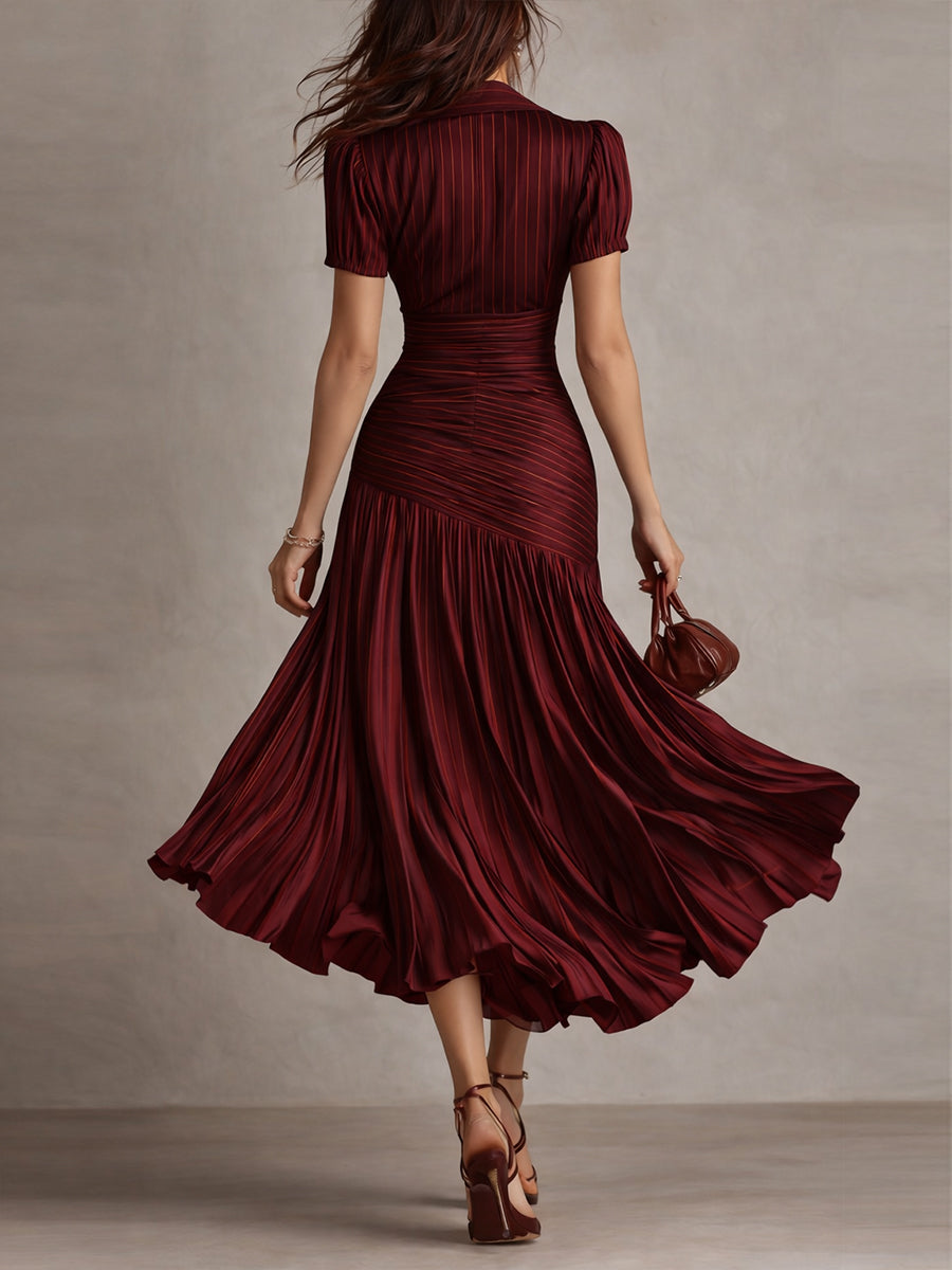 Back view of model in burgundy midi dress with detailed pleats and short sleeves, walking in a neutral studio.
