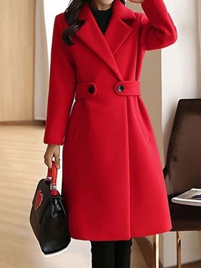 Chic red coat featuring button accents and wide lapels, showcased indoors. Model carries a black handbag with red handles.