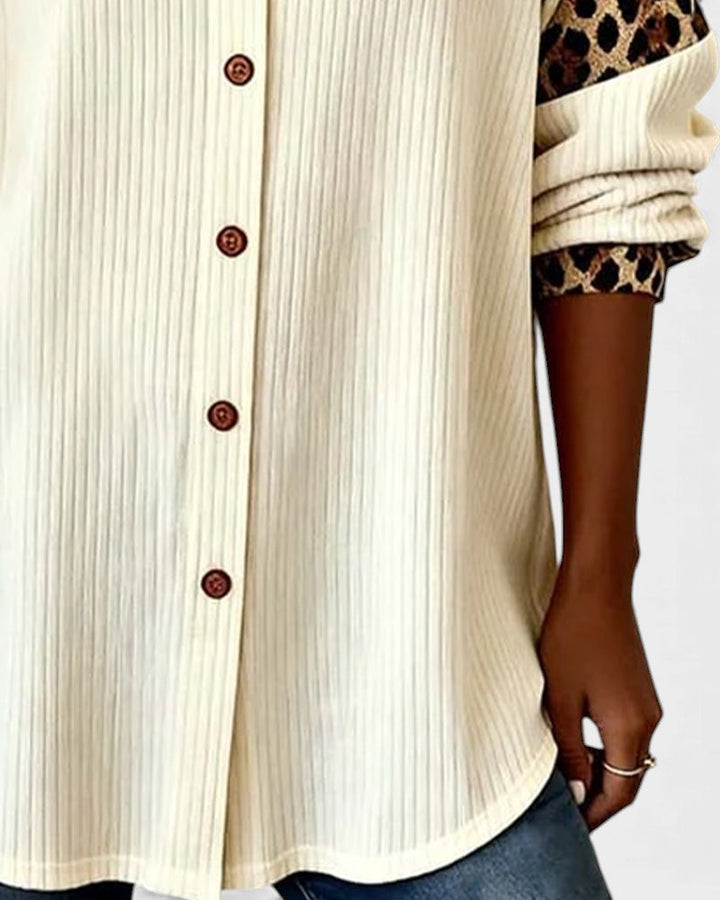 Close-up of leopard print button-down shirt bottom. Cream shirt with brown buttons and patterned cuffs in a studio.