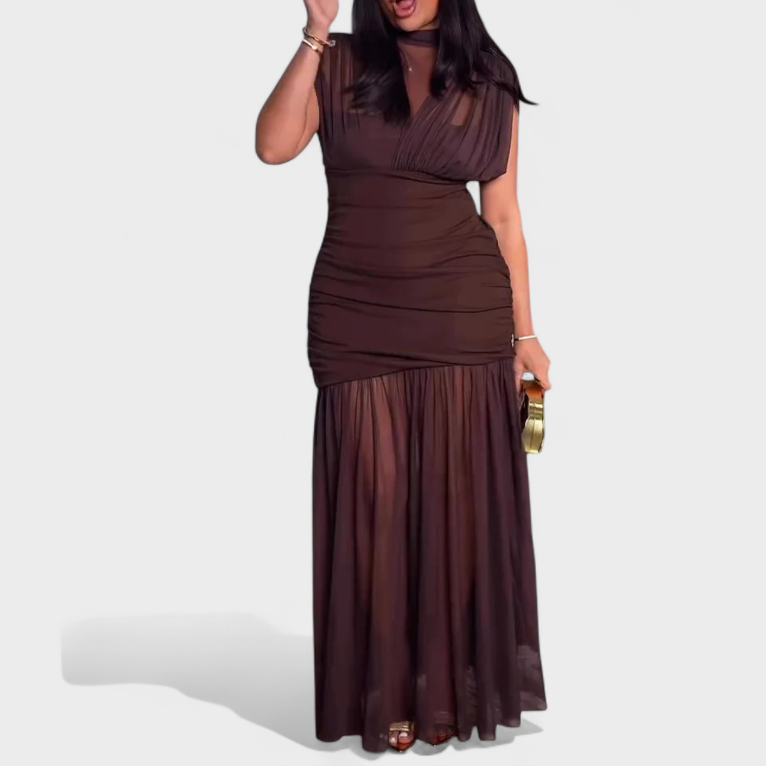 Model wearing a chic brown dress with pleated details and sheer elements in a studio.