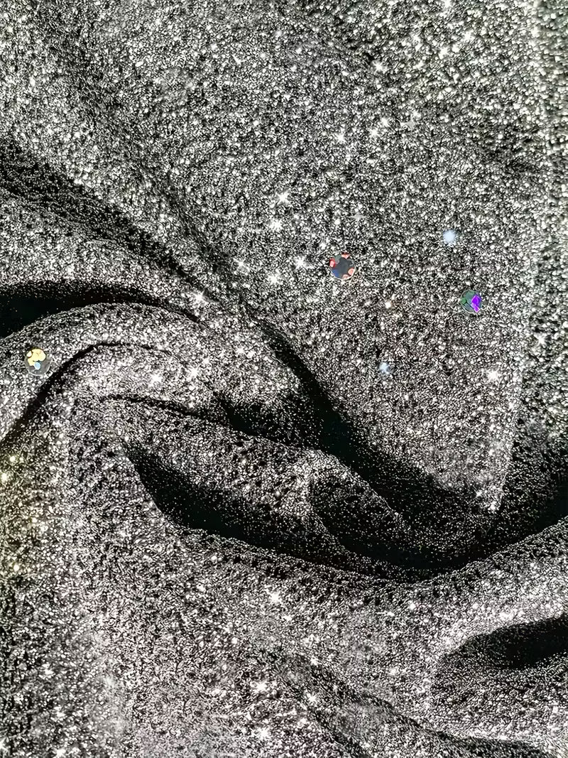 Detailed view of grey dress fabric featuring sparkling dots and folds, showcasing texture and shine.