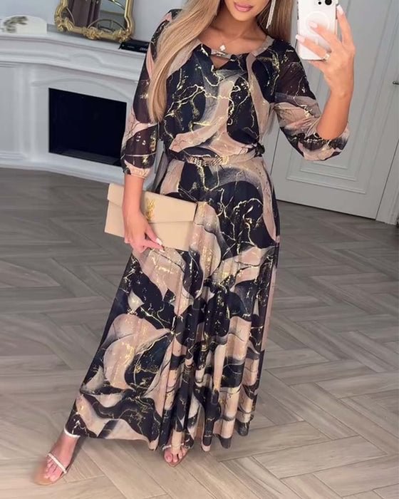 Flowing black and beige dress with abstract pattern, worn in elegant indoor setting with parquet flooring.