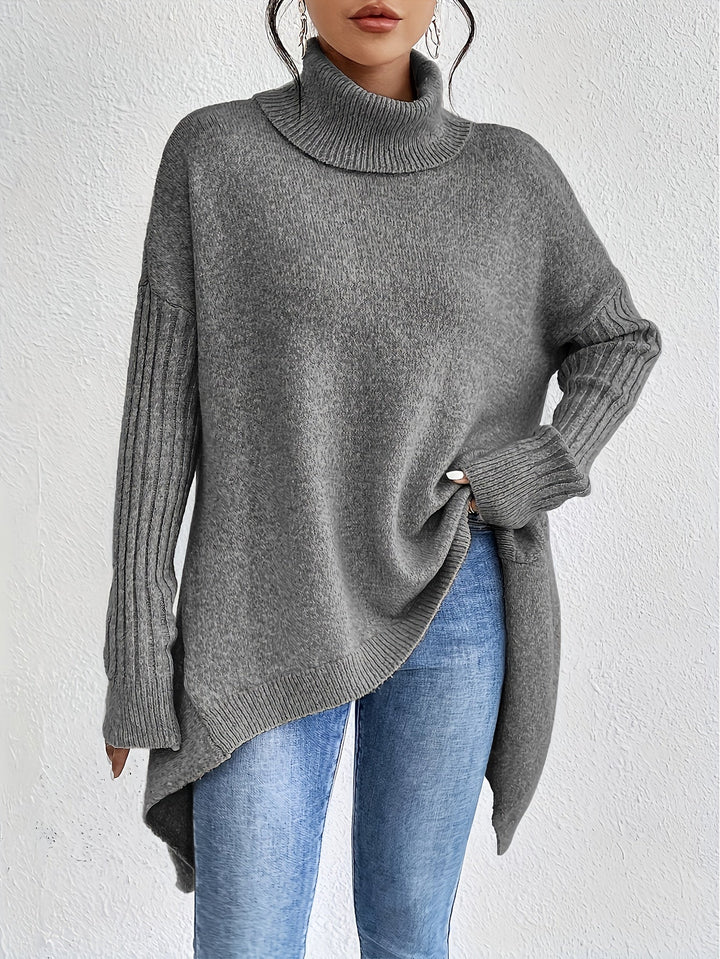 Gray sweater with turtleneck and long ribbed sleeves, styled with jeans, against a white backdrop.