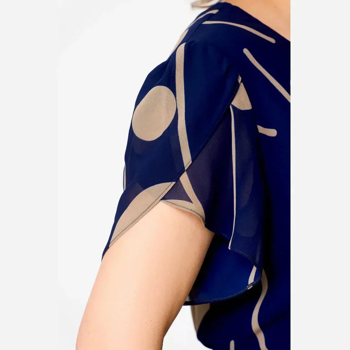 Close-up of navy polka dot chiffon dress sleeve, showing sheer fabric and polka dot detail in a studio setting.
