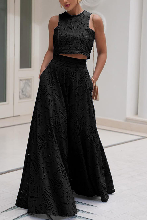 Woman in a black embroidered top and high-waist maxi skirt standing indoors with a neutral background.