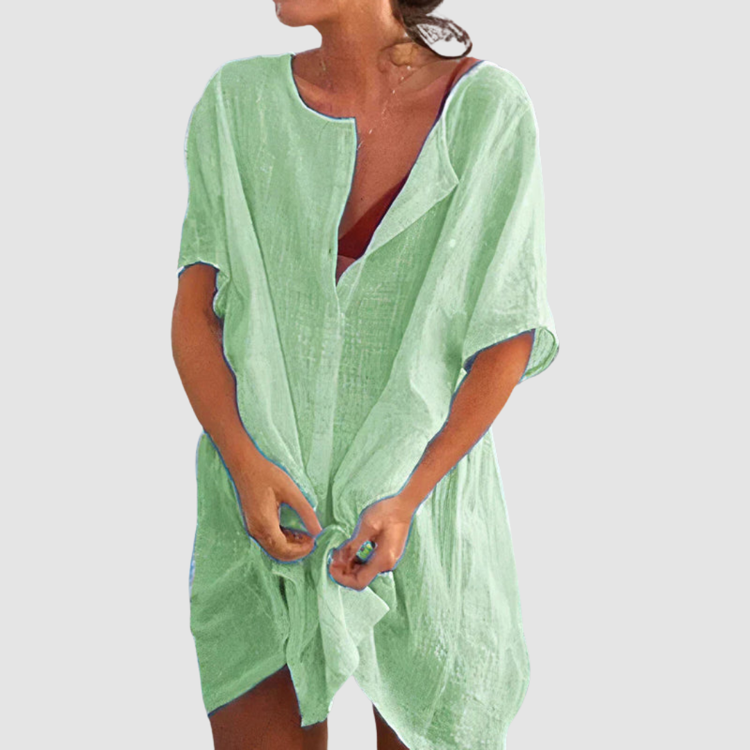 Green loose fit dress with short sleeves and textured fabric, worn by person with untied front, studio background.