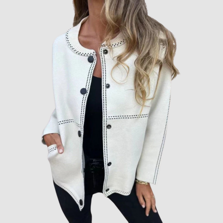 Cream jacket with round collar, button closure, worn over black top and pants in a studio setting.