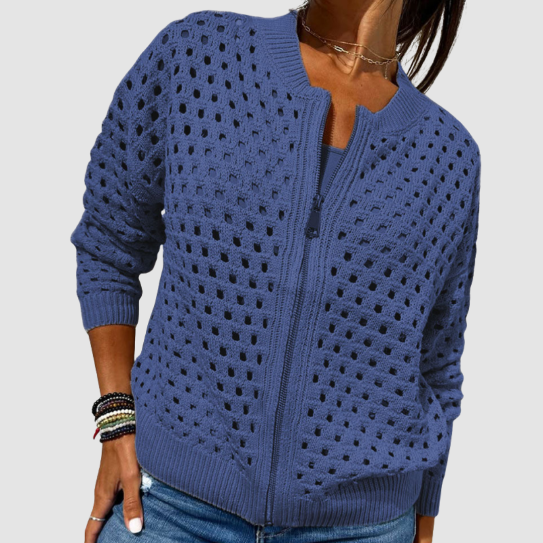 Blue knitted cardigan with a zip closure and perforated detail, styled with casual denim in a studio setting.
