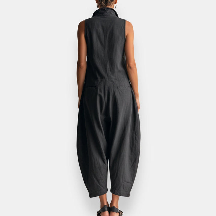 Back view of black sleeveless cargo jumpsuit with relaxed fit, worn by a model standing, studio background.