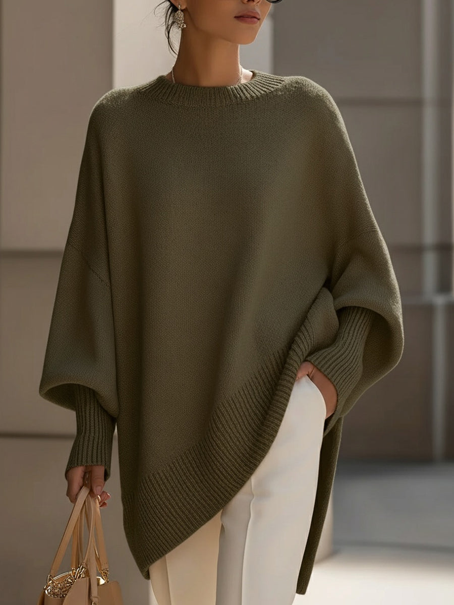 Woman in an oversized green sweater with ribbed hem and cuffs, holding a bag, in an urban setting.