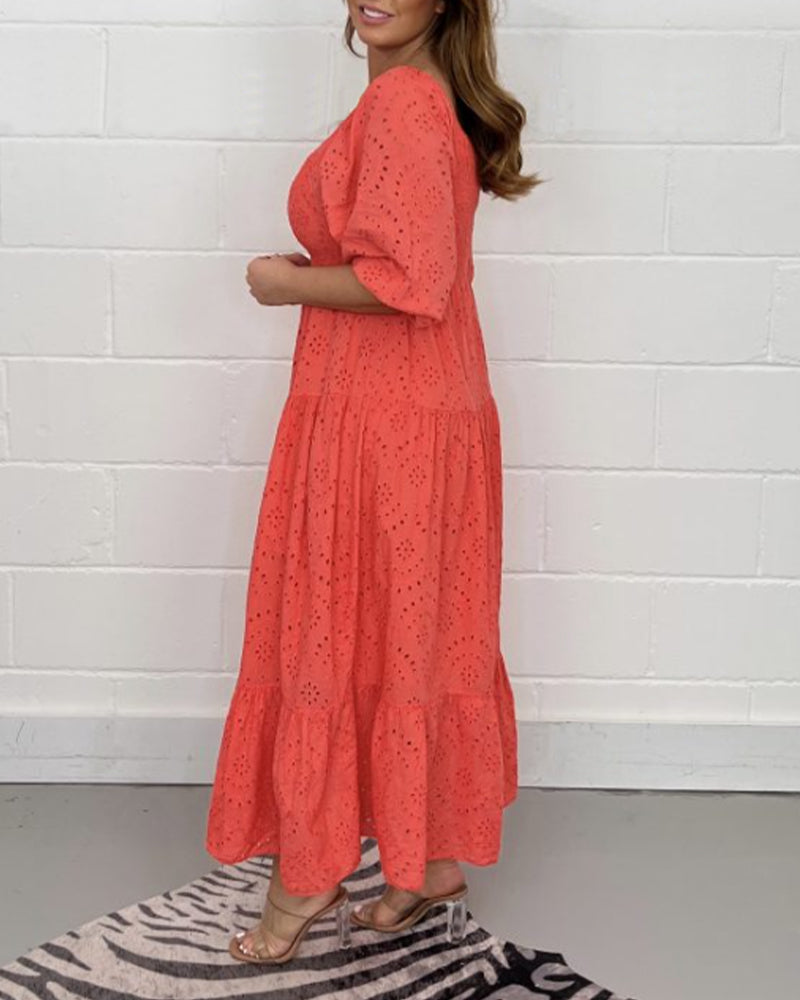 Side view of red dress with eyelet design, modeled indoors with neutral wall background.