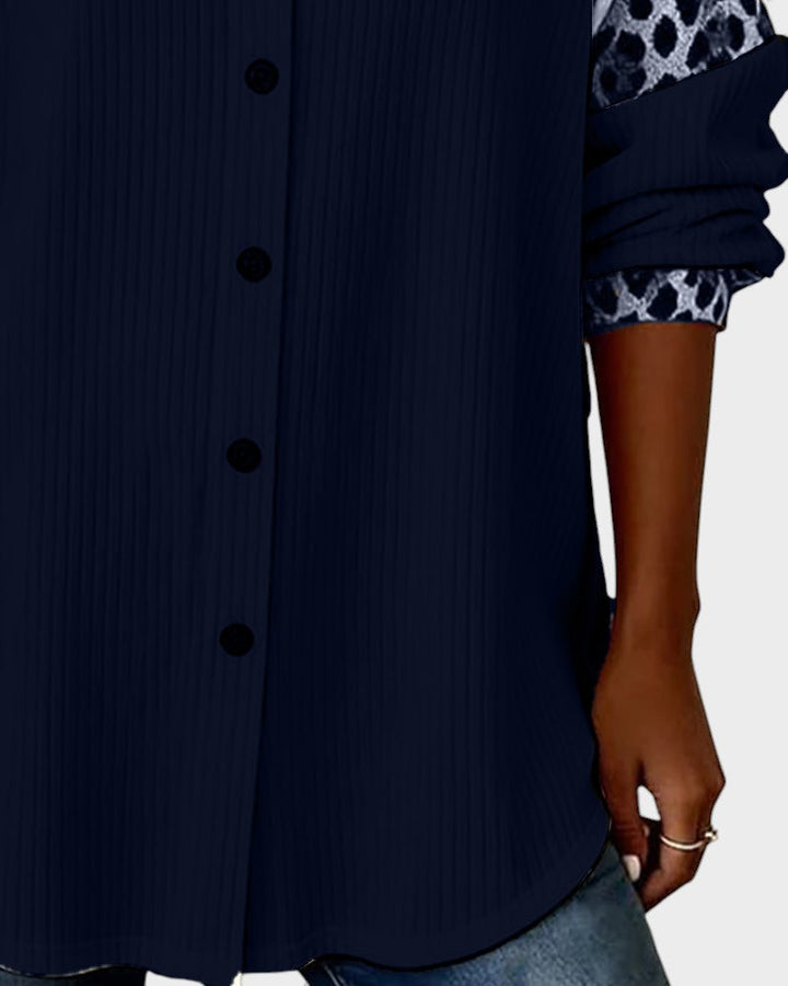 Close-up of leopard print button-down shirt bottom. Navy shirt with black buttons and patterned cuffs in a studio.