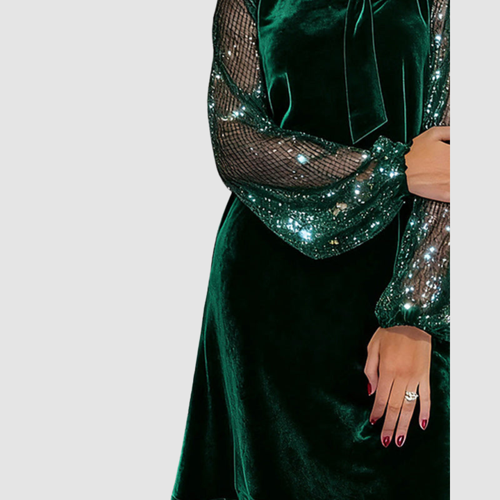 Partial view of green dress with shimmering mesh sleeve and bow detail, worn by a model, on a gray background.