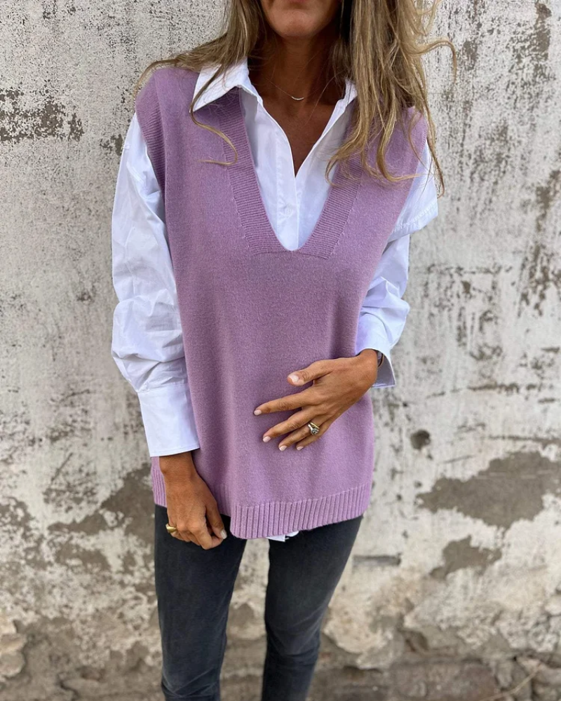 Purple knit vest over a white shirt, person standing in front of a distressed wall.