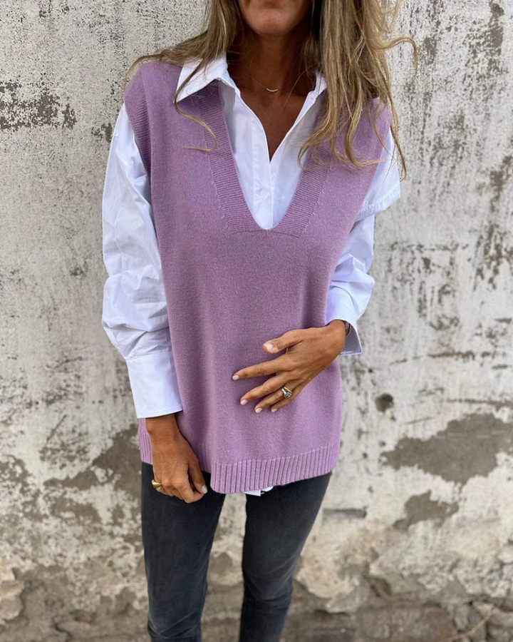 Purple knit vest over a white shirt, person standing in front of a distressed wall.