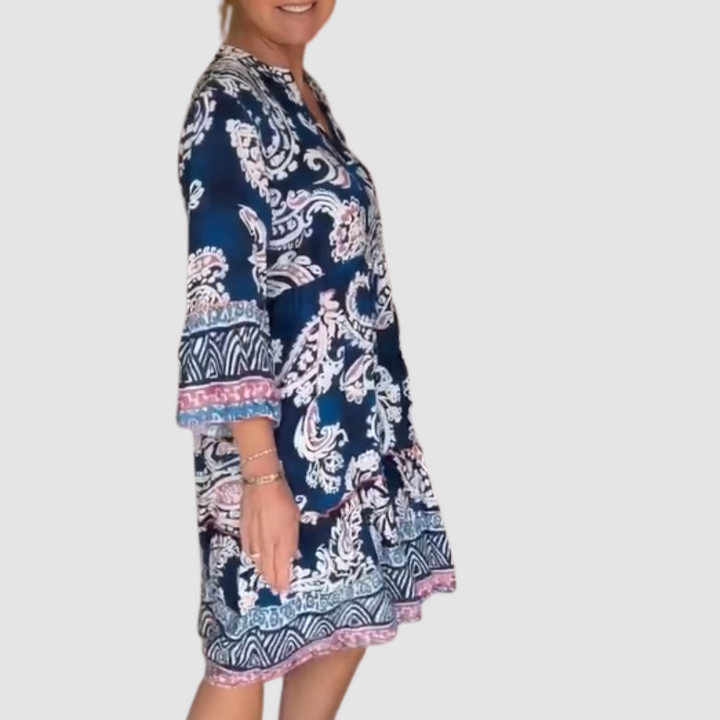 Side view of blue, pink paisley V-neck dress with 3/4 sleeves in a studio setting.