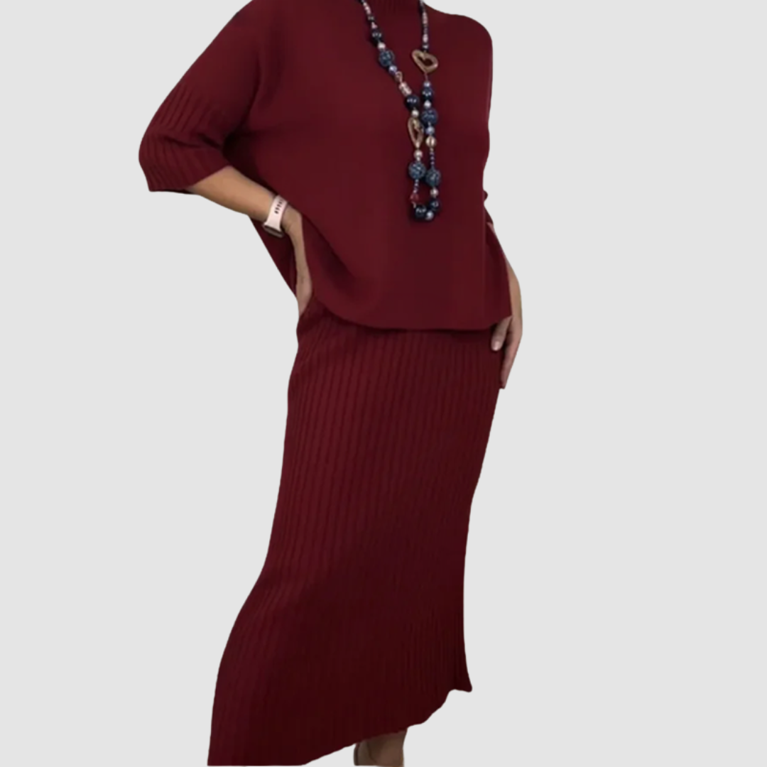 Maroon 2-piece set with ribbed skirt and loose top, accessorized with a beaded necklace on plain background.