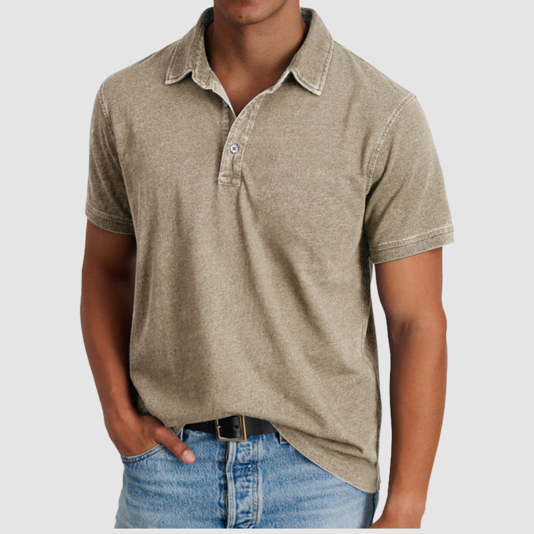 Model in a beige classic collared polo, short sleeves, buttoned placket, paired with light denim jeans, studio setting.