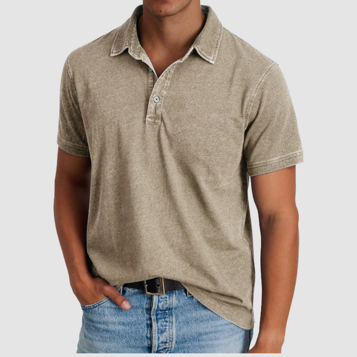 Model in a beige classic collared polo, short sleeves, buttoned placket, paired with light denim jeans, studio setting.