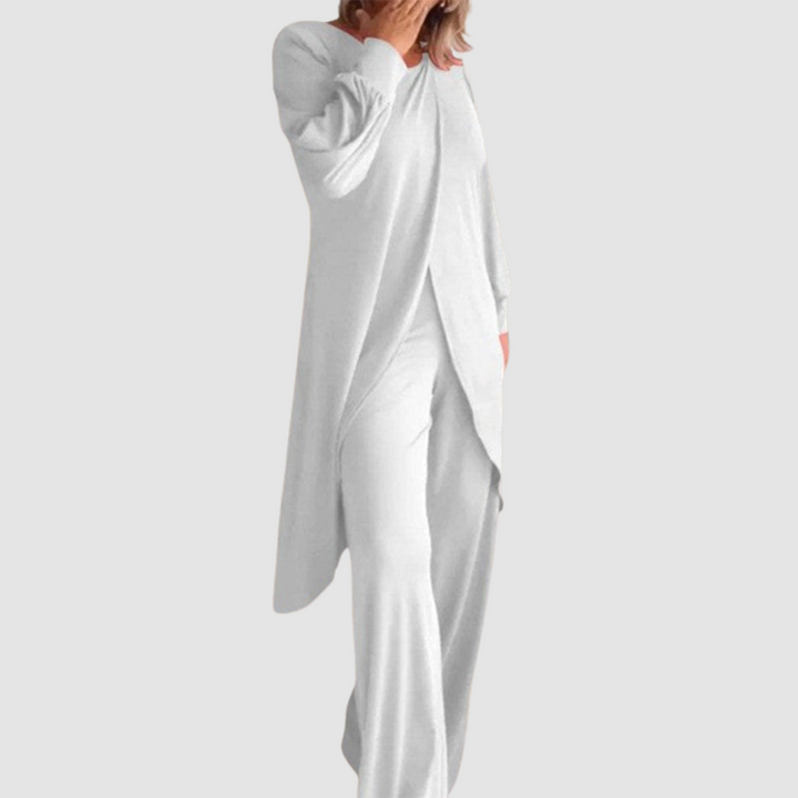 Model wearing a white long-sleeve 2-piece set in a studio, hand covering face, white background.