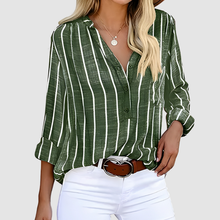 Green and white vertical striped blouse with rolled-up sleeves, paired with a belt and white pants. Studio background.