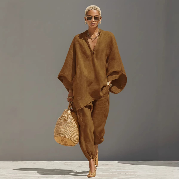 Model wearing brown batwing sleeve V-neck lounge set with straw bag, studio background.