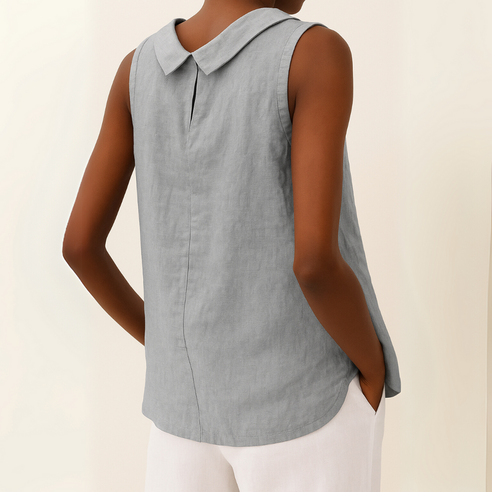 Back view of grey sleeveless top with roll collar, model wearing white pants, light background.