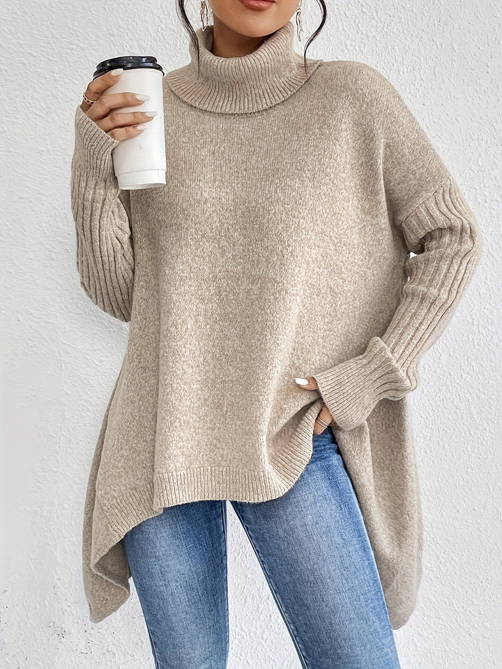 Beige turtleneck sweater with ribbed sleeves, holding a coffee cup, styled with jeans in front of a white background.