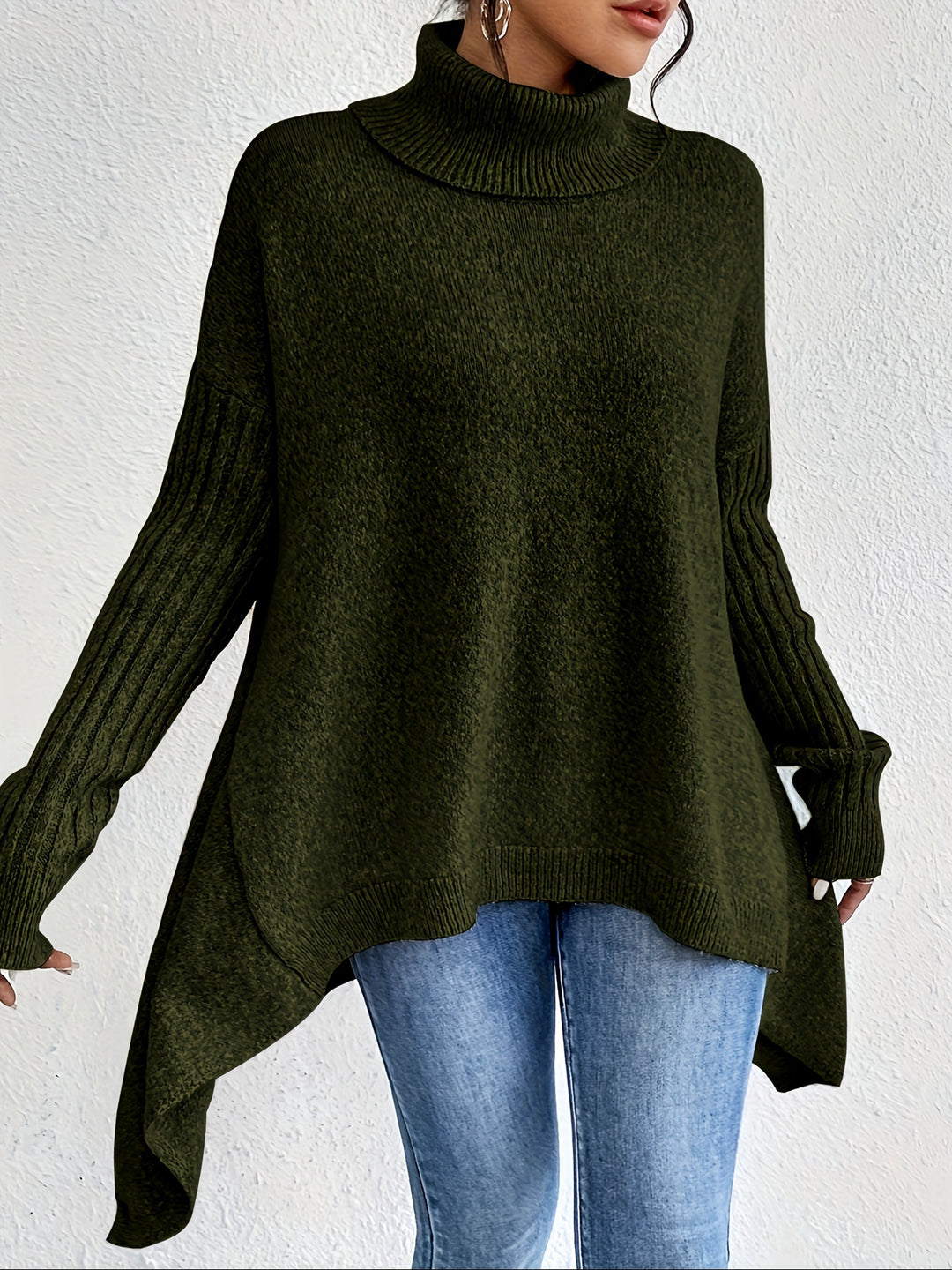Green turtleneck sweater with long sleeves, styled with jeans, positioned in front of a plain white wall.