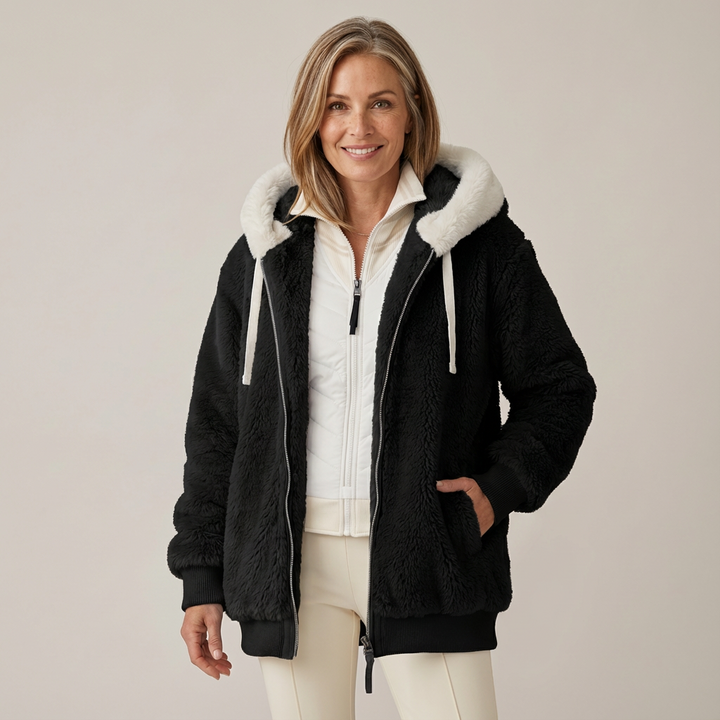 Woman wearing a fluffy black hooded jacket with white lining, in a studio setting.