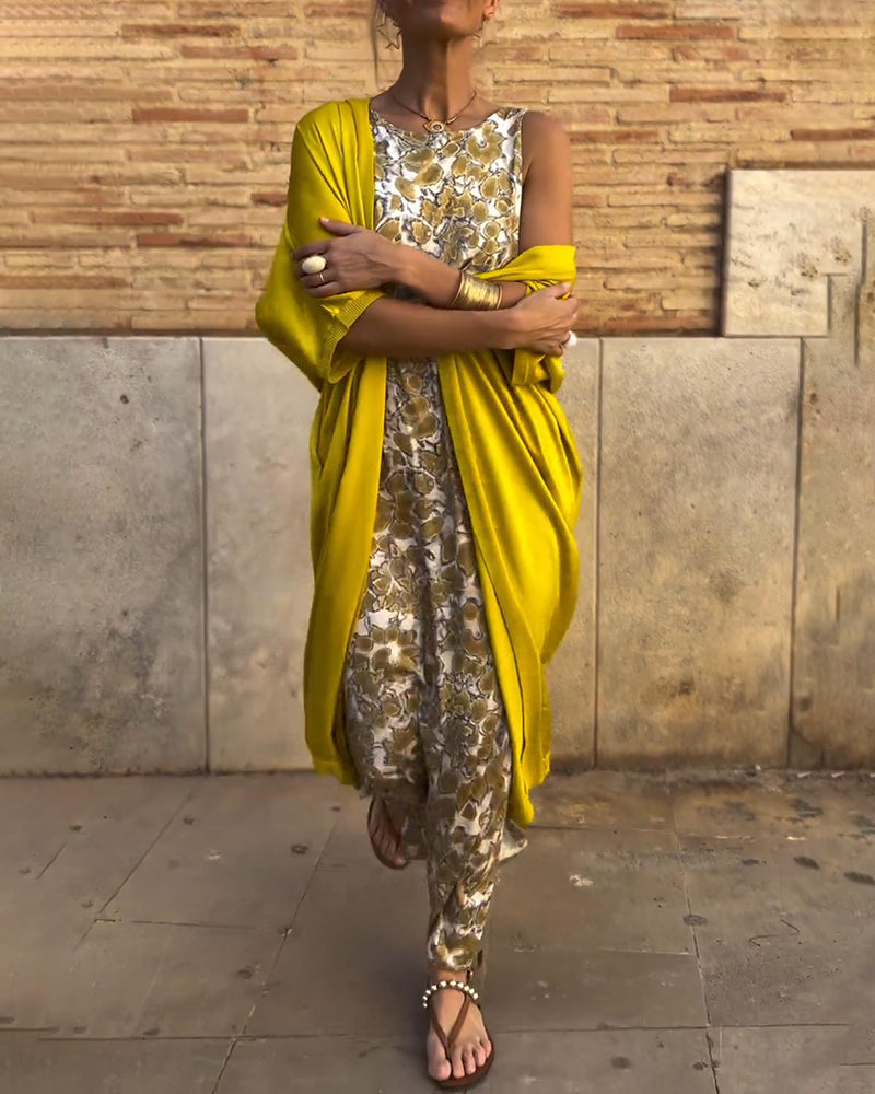 Person wearing a floral patterned two-piece set with a bright yellow shawl, standing on an urban street.