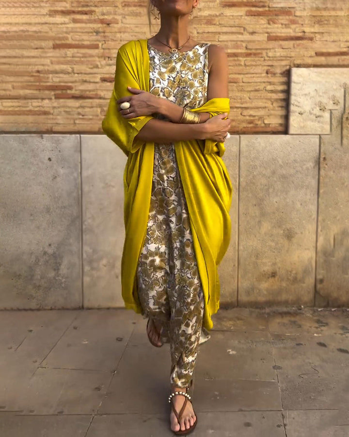 Person wearing a floral patterned two-piece set with a bright yellow shawl, standing on an urban street.